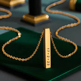 Sleek Gold Bar Pendant Necklace engraved with a custom date '17.2.23', displayed on a green velvet surface, perfect for memorable gifting.